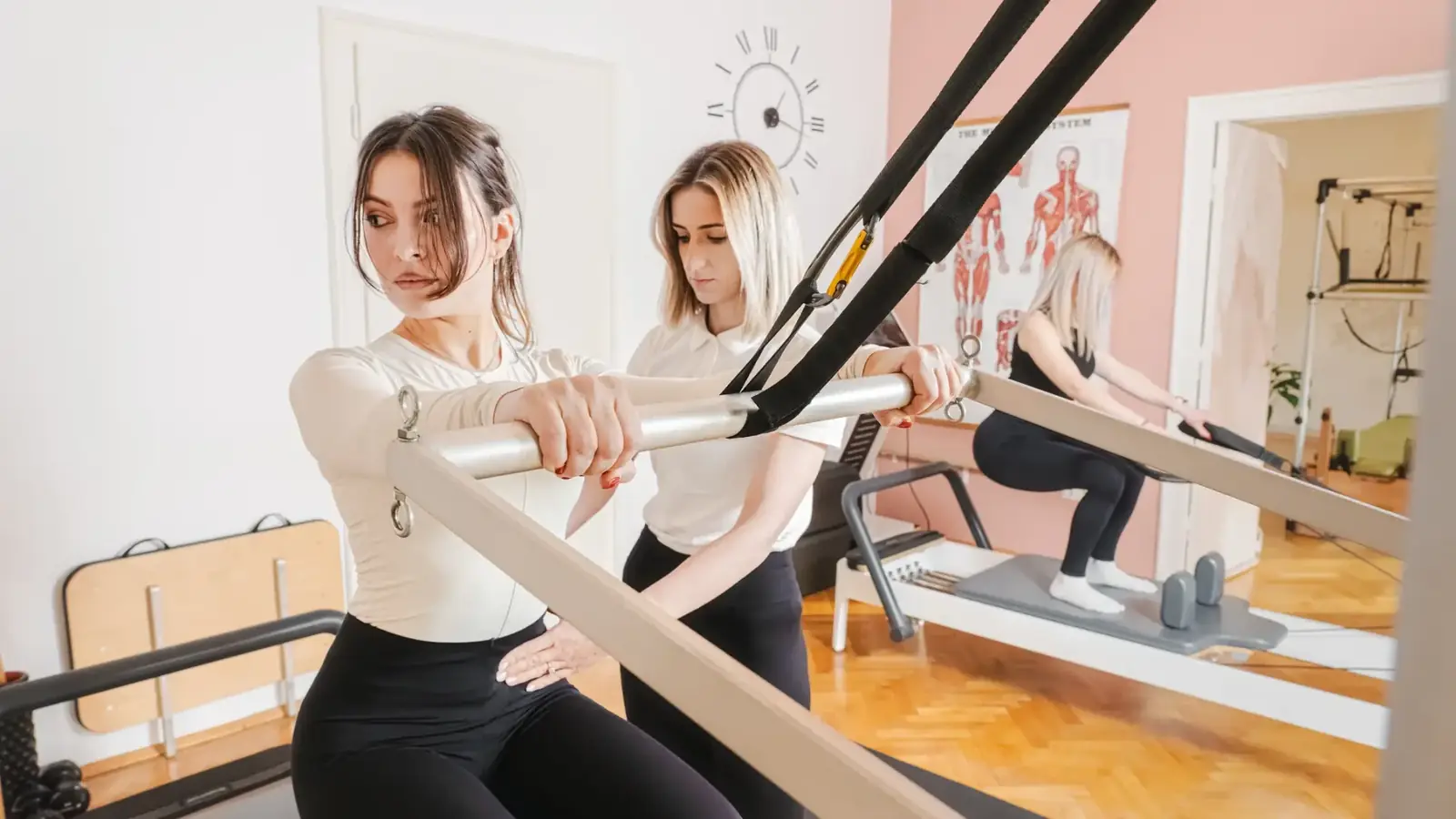 Instructoare Pilates Cluj asistând o clientă la aparatul reformer